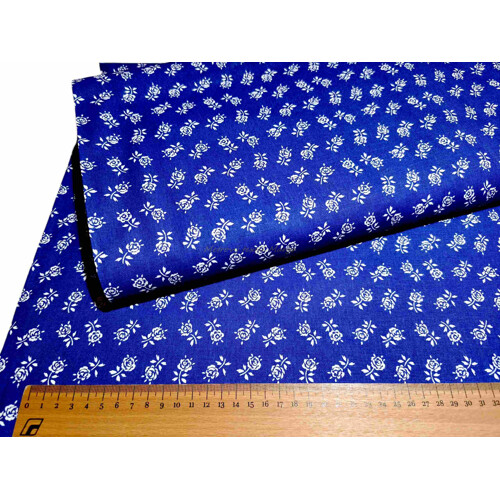 Detail bavlneného plátna v modrej farbe s tradičným folklórnym vzorom bielych ružičiek. Nadčasová metráž na šitie vidieckych dekorácií a šiat, šírka 150 cm